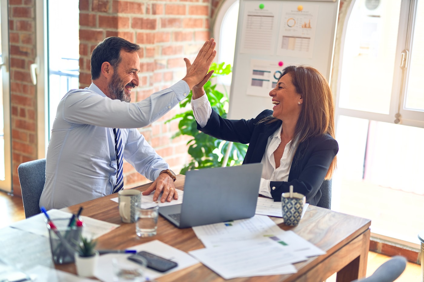 Two colleagues celebrating a funded loan approval in an office