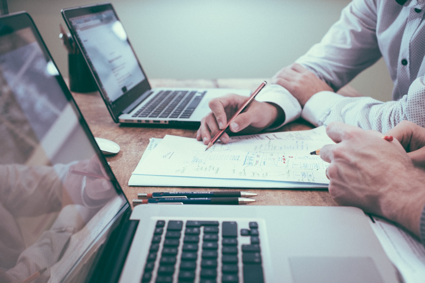 Two lending professionals reviewing a loan file together at a desk with laptops